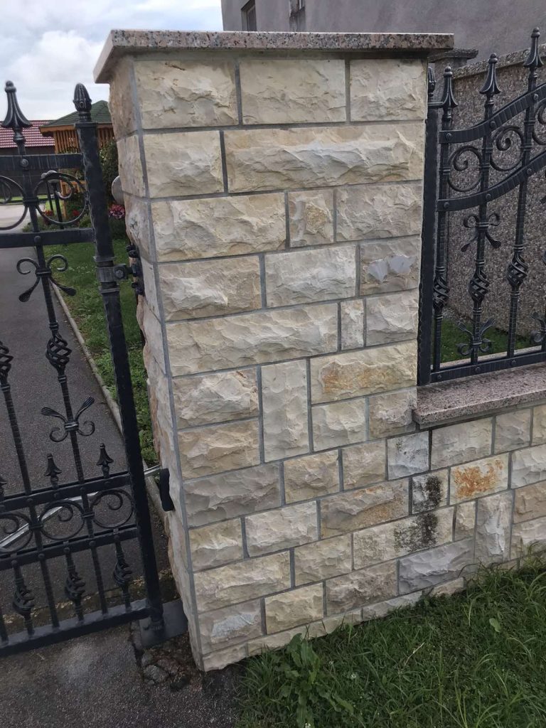 Ogradni zid i stup obloženi bunjom uz metalnu ogradu